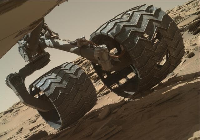 Curiosity rover's aluminium wheels on the rocky Martian terrain showing wear patterns
