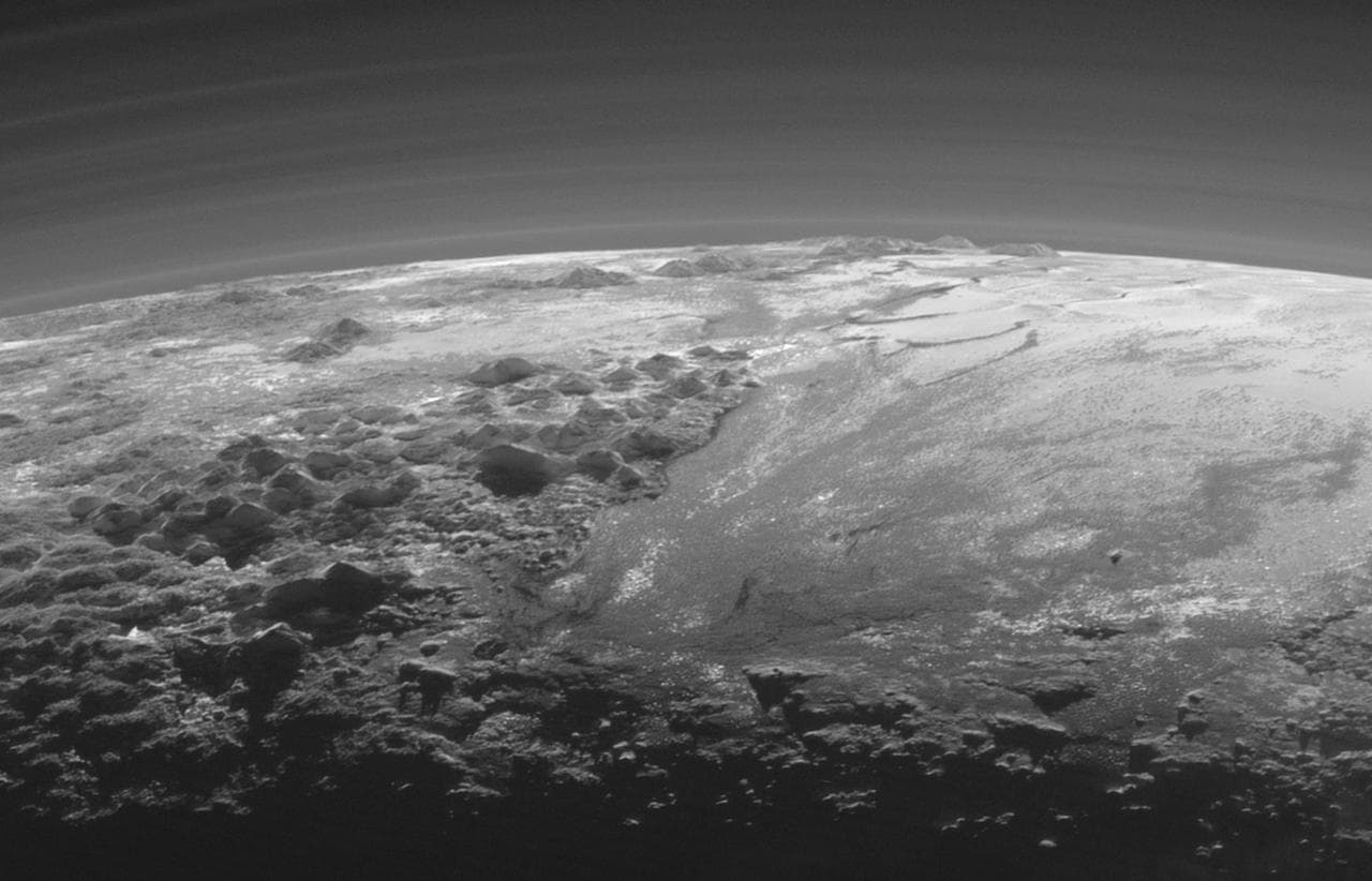 Pluto in enhanced colour photographed by New Horizons, showing its complex terrain and thin atmosphere