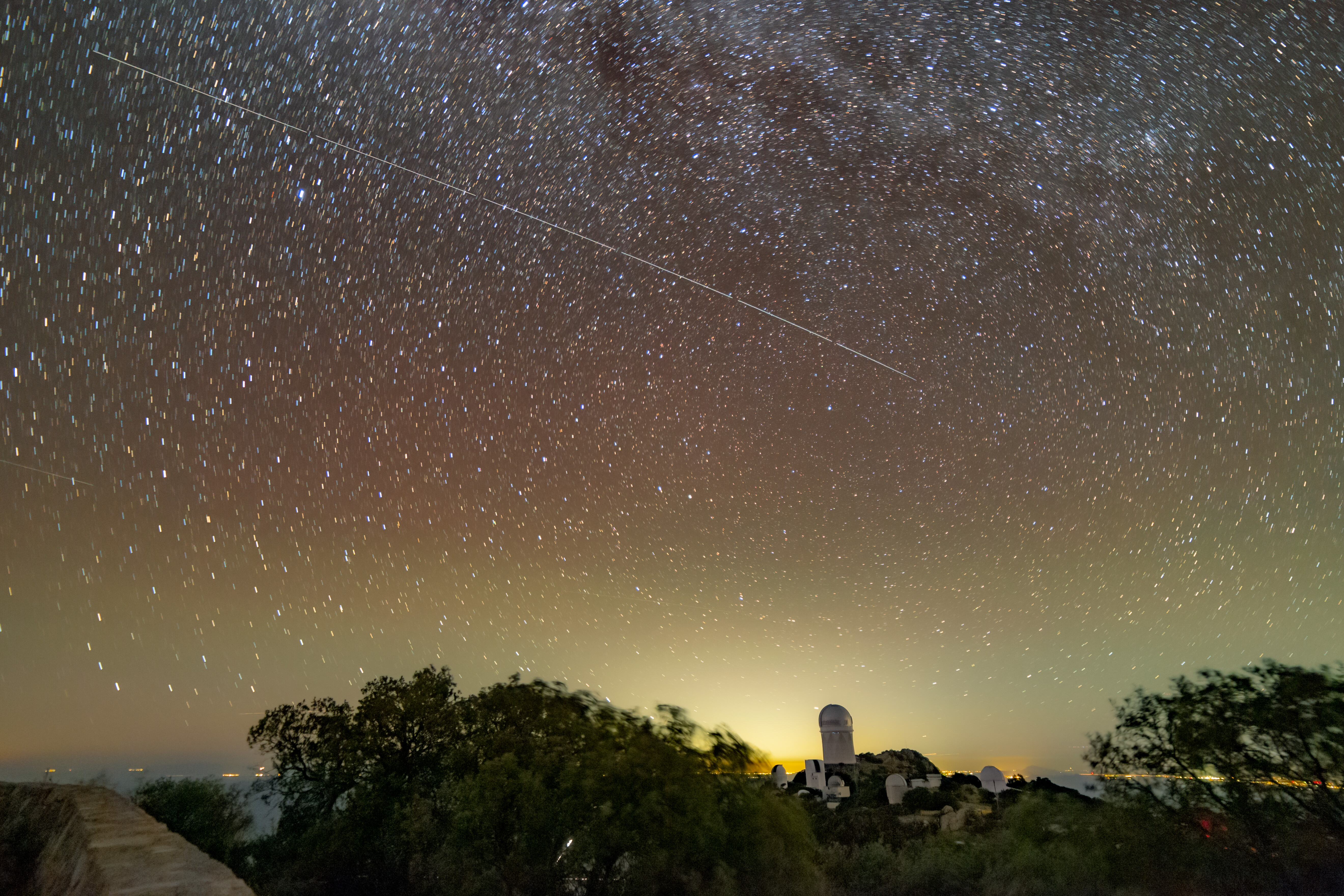 Light trail left by AST SpaceMobile's BlueWalker 3 satellite crossing the night sky above the Mayall 4-meter Telescope at Kitt Peak National Observatory in November 2022