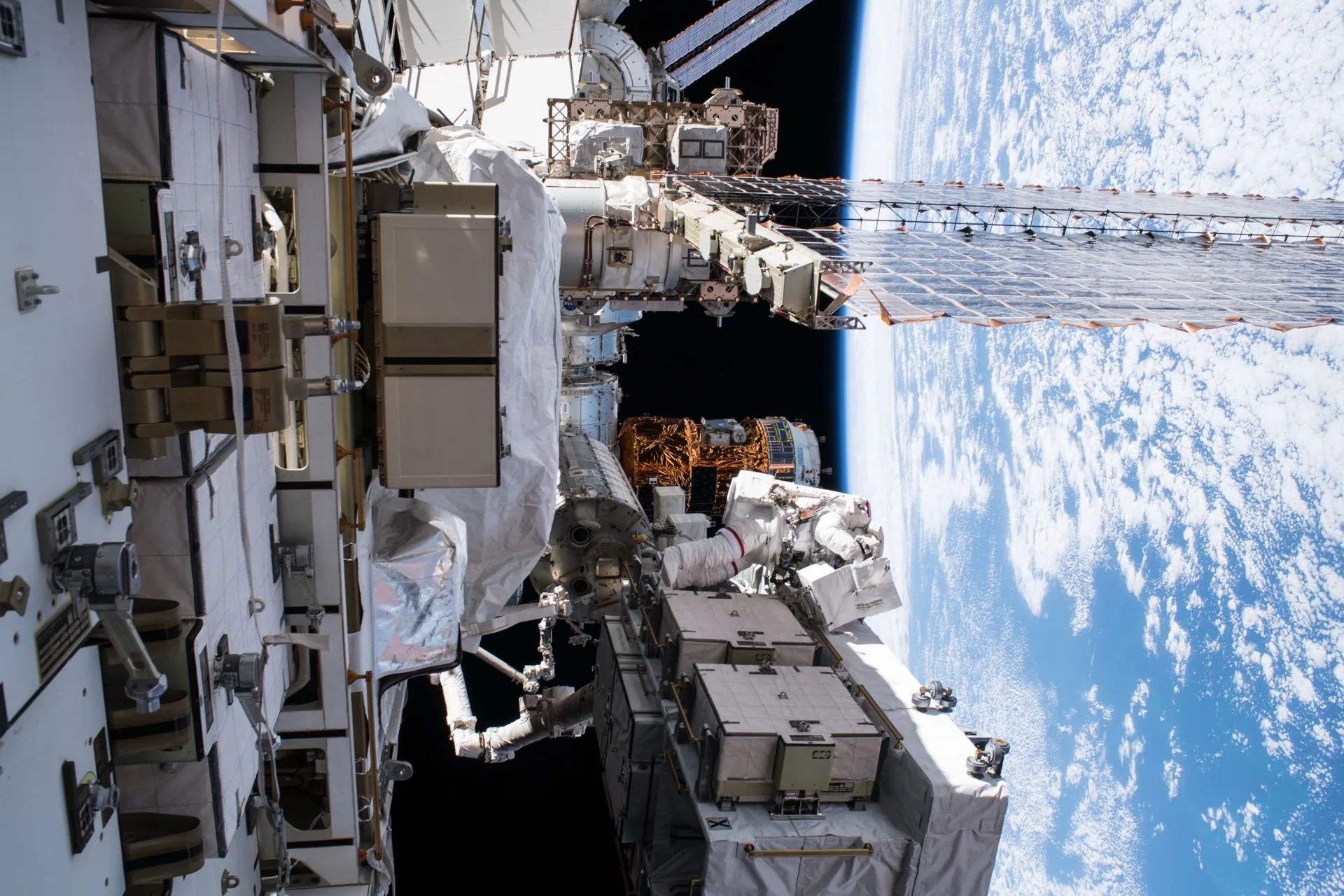 An astronaut conducts a spacewalk (EVA) with Earth's curved blue horizon visible below — one of the rarest and most demanding professional experiences