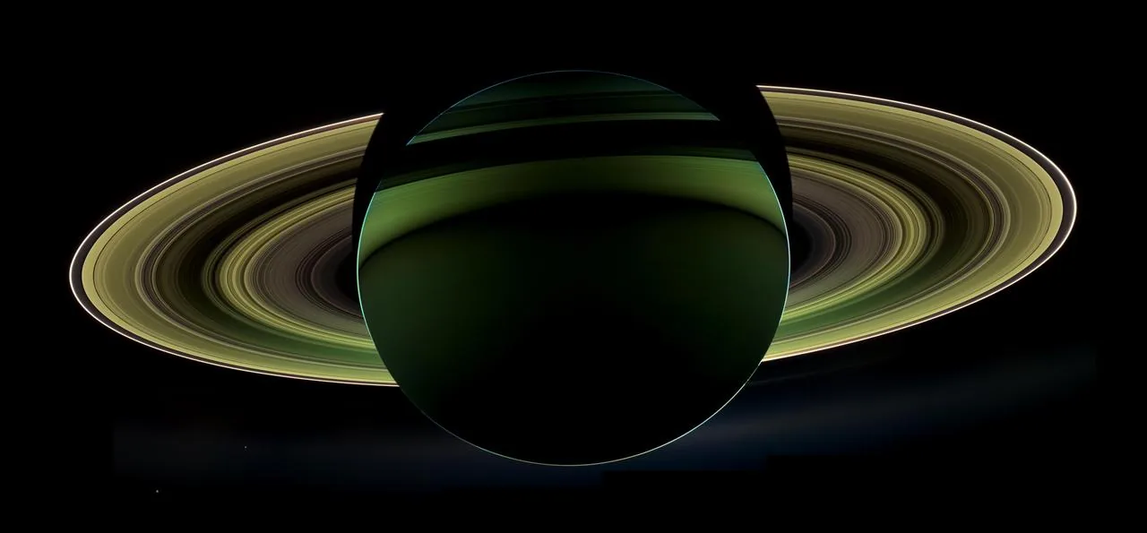 Cassini's iconic backlit view of Saturn — rings illuminated with Earth visible as a pale blue dot between them