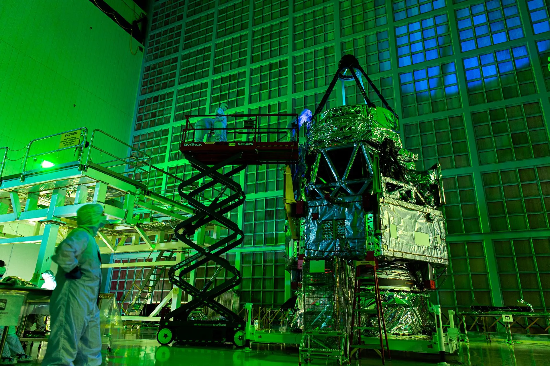 Roman Space Telescope team members inspect the primary mirror using UV lights in the Goddard cleanroom, July 2025