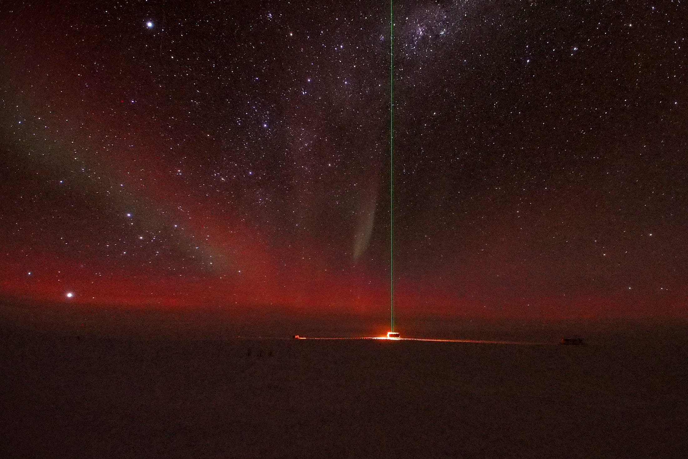 Green aurora australis and a vertical lidar laser beam over a snow shelter at Dome C, Antarctica