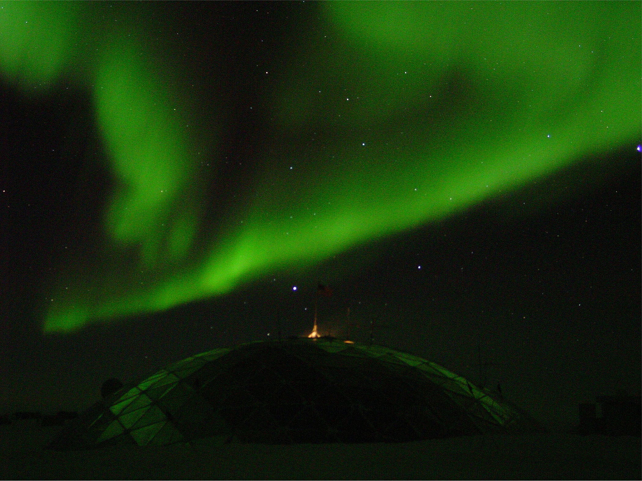 Green southern lights above the geodesic dome of the South Pole station in Antarctica