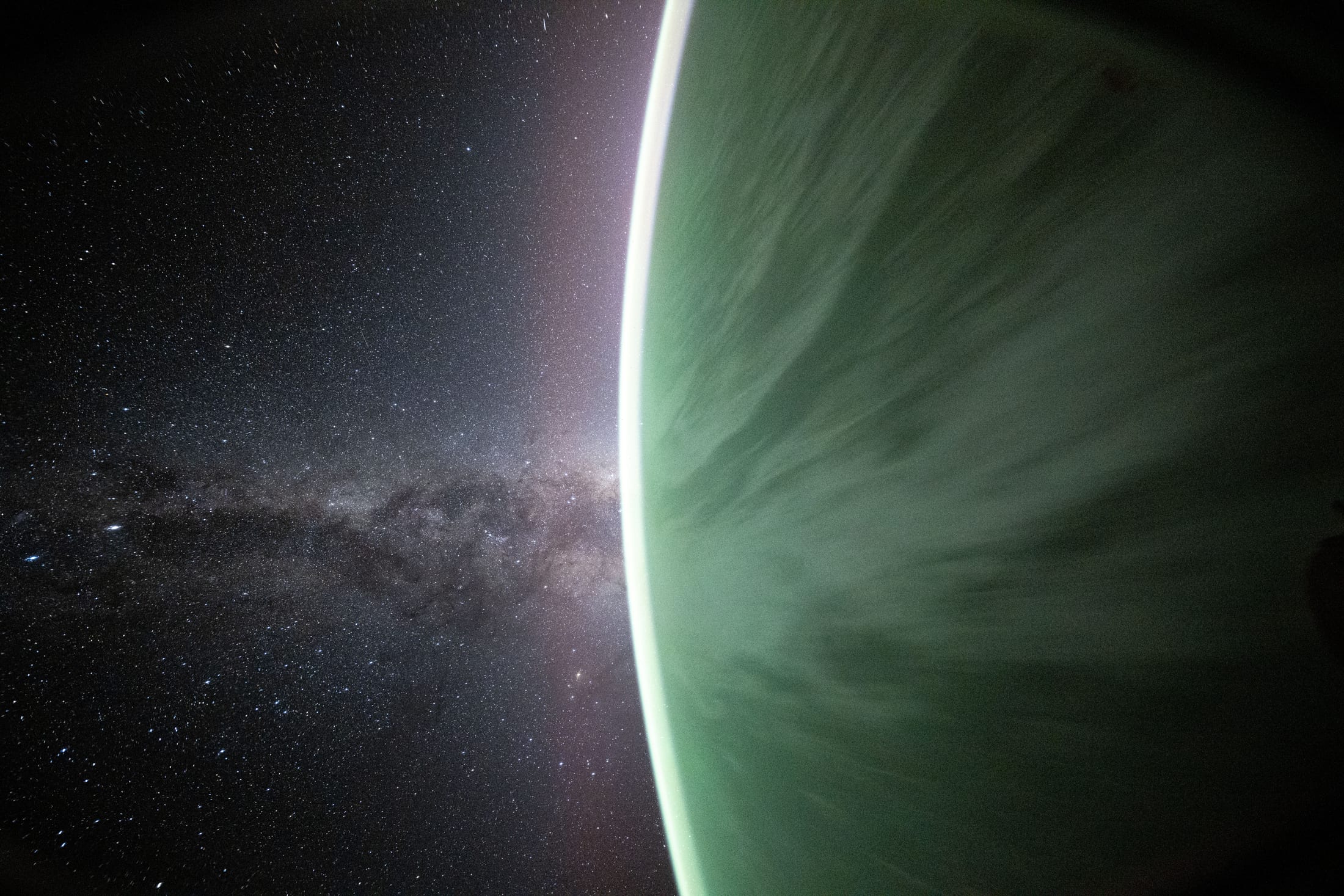 The Milky Way rising beyond Earth's green aurora limb, seen from the ISS