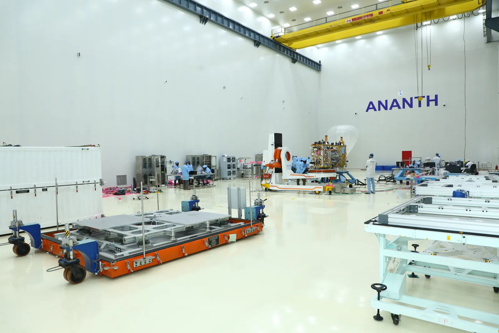 Wide interior view of Ananth Technologies' satellite Assembly, Integration & Testing cleanroom in Bengaluru — a gold-foil-wrapped spacecraft on an integration stand under an overhead crane.