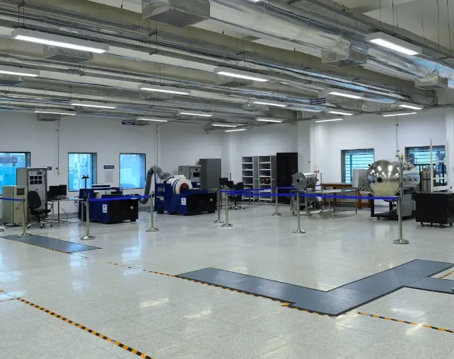 Interior of Azista BST Aerospace's satellite test facility, with a vibration table and thermal-vacuum chamber on the production floor.