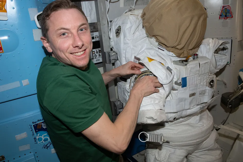 NASA astronaut Woody Hoburg services an EMU and its life-support backpack inside the ISS Quest airlock ahead of a spacewalk.