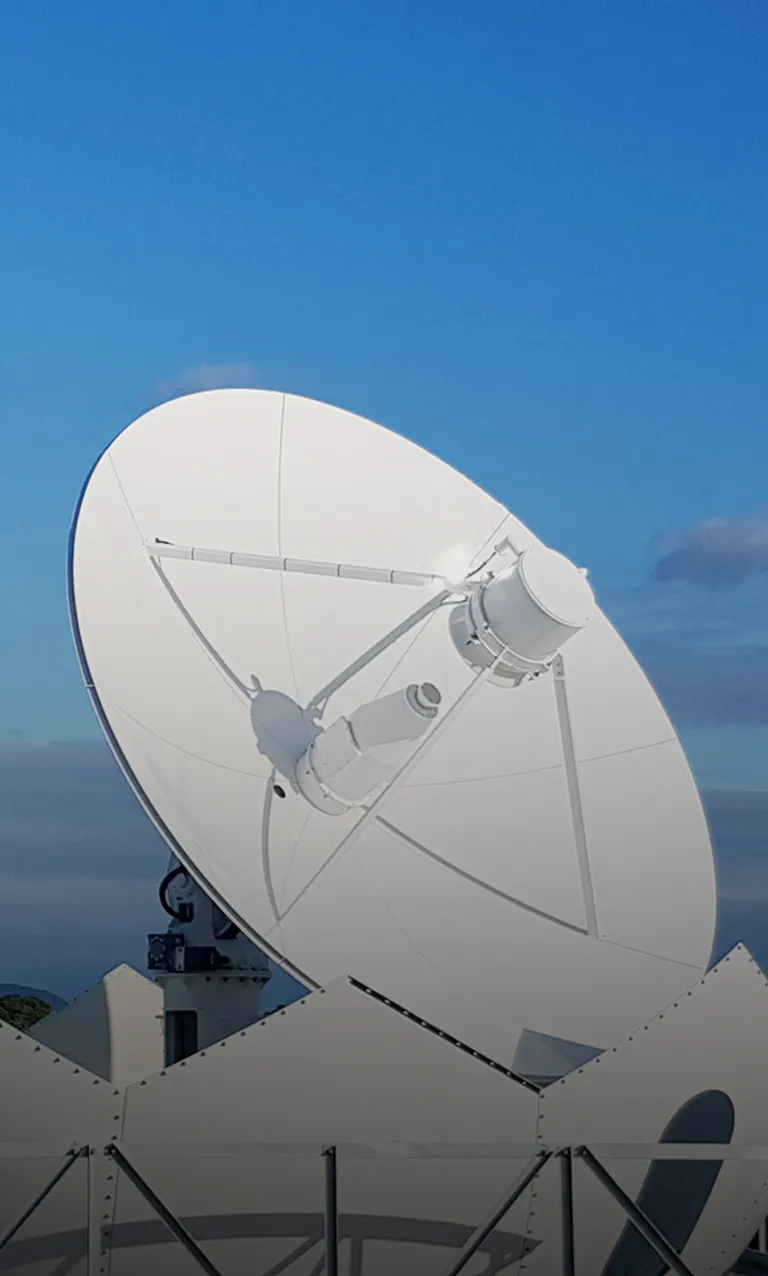 A Contec white parabolic satellite ground-station antenna dish against a blue sky, part of its global GSaaS network.