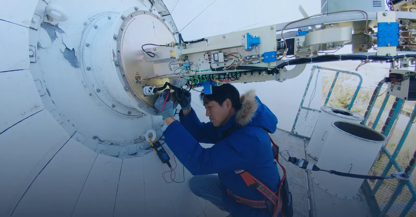A Contec engineer services the feed electronics at the rear of a satellite ground-station antenna dish — Contec operates a global Ground-Station-as-a-Service network.
