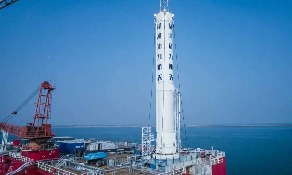 A Galactic Energy Ceres-1 rocket stands vertical on its sea-launch barge off Shandong, the company's livery painted down the fuselage.