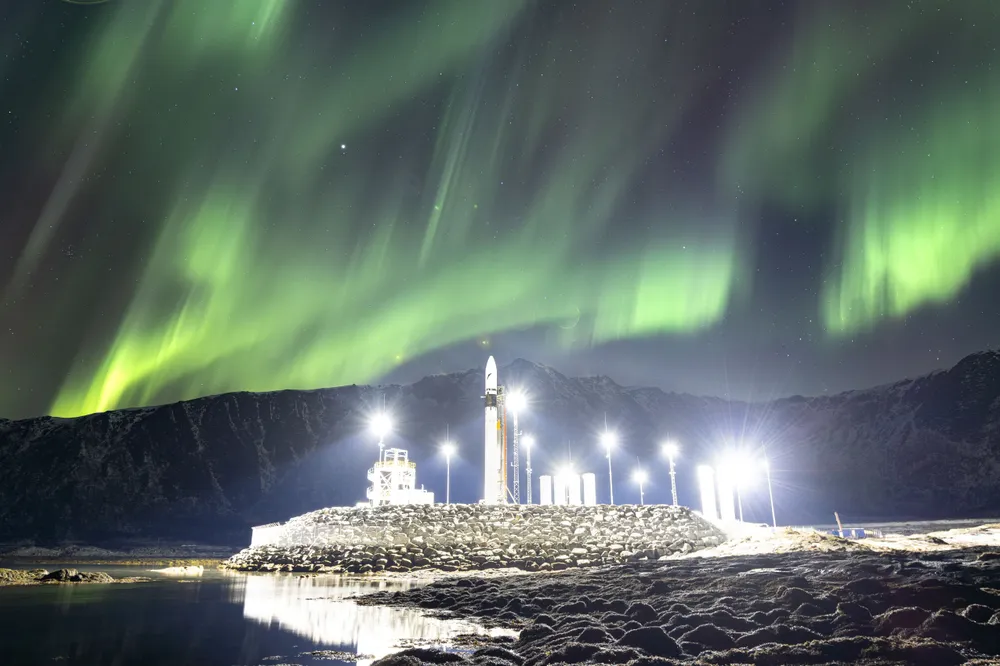 Isar Aerospace's Spectrum rocket on the launch pad at Andøya Spaceport, Norway, beneath the aurora borealis.