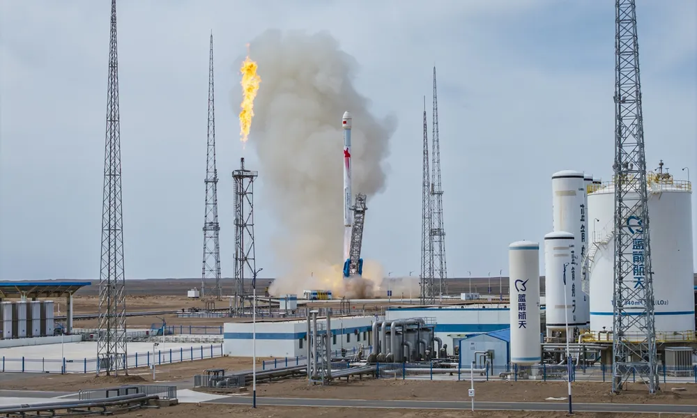 LandSpace's Zhuque-2E methalox rocket lifts off from the Dongfeng commercial pad on 14 May 2026, with the propellant flare stack burning and 'LandSpace' liquid-oxygen tanks in the foreground.