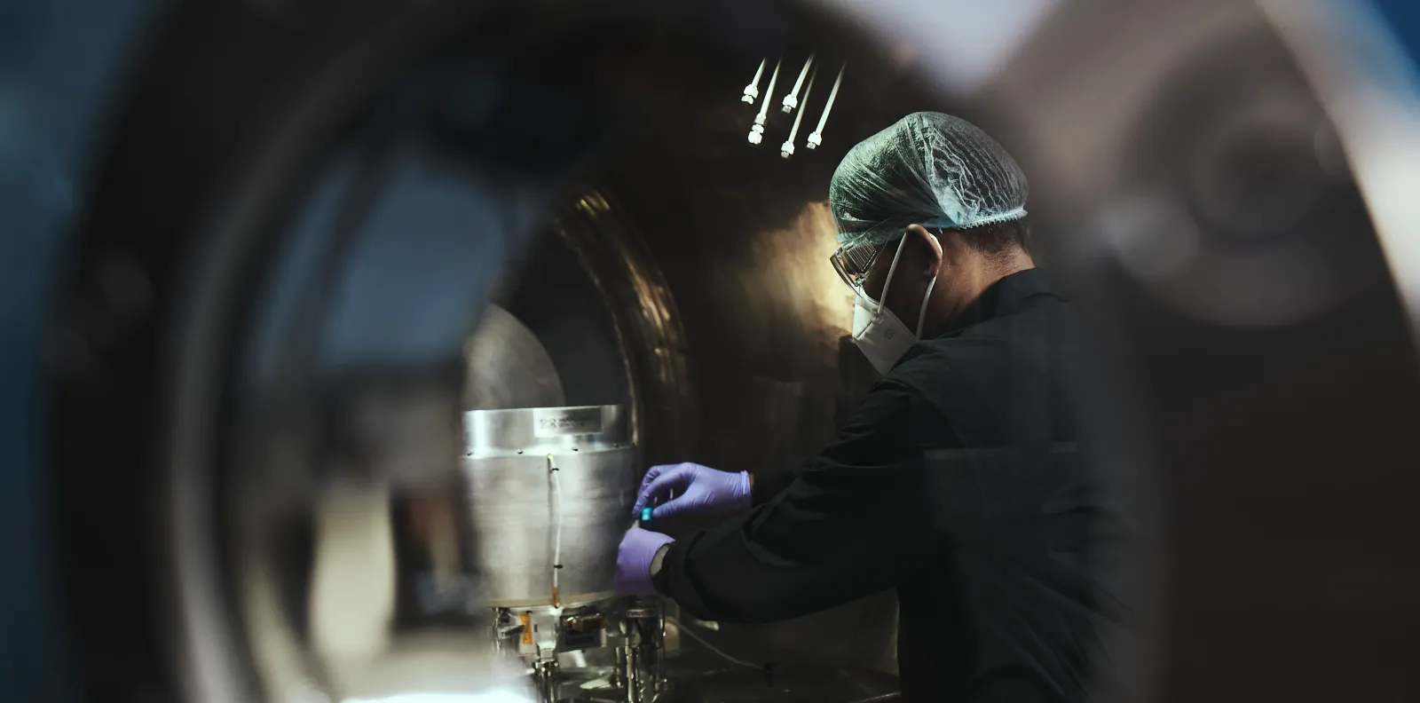 A Manastu Space engineer in cleanroom gear assembles green-propulsion hardware inside a test chamber — Manastu builds non-toxic (MS-289 / hydrogen-peroxide) satellite propulsion.