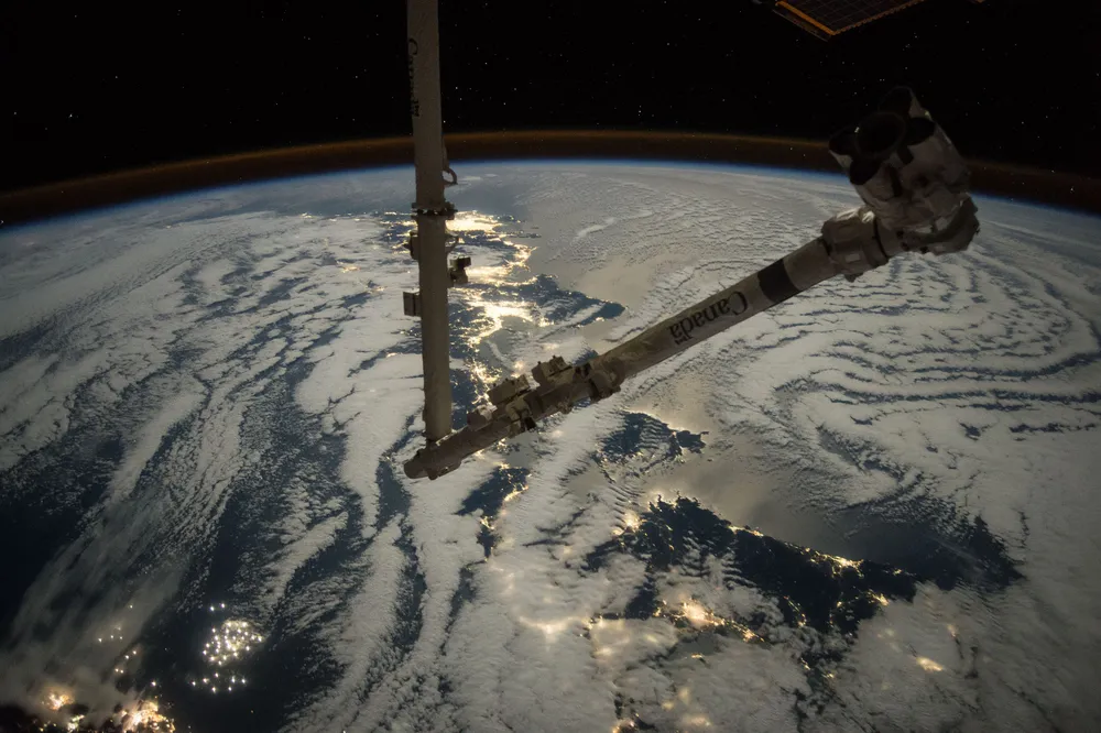 Canadarm2 extended above Earth, photographed from the ISS.
