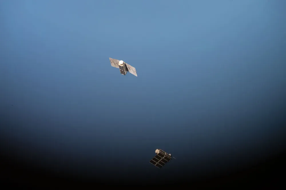 Planet Labs Dove nanosatellites released from the ISS, drifting toward Earth.