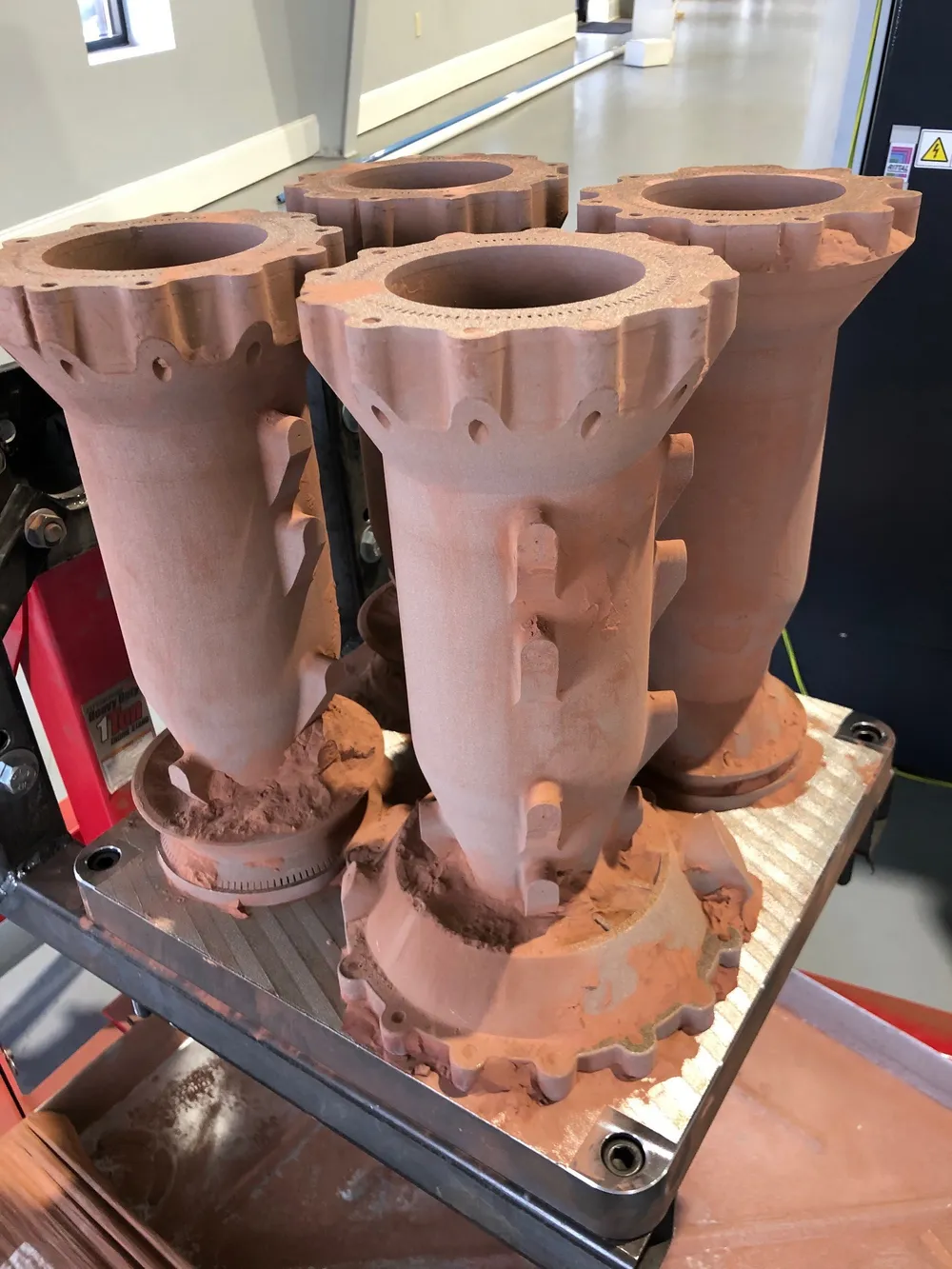 An additively-manufactured rocket combustion chamber shown mid-fabrication.