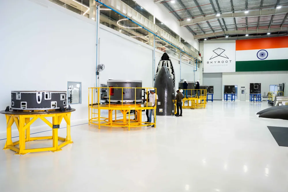 Interior of Skyroot Aerospace's rocket integration facility, with stage hardware on yellow handling stands and the Indian flag on the wall.