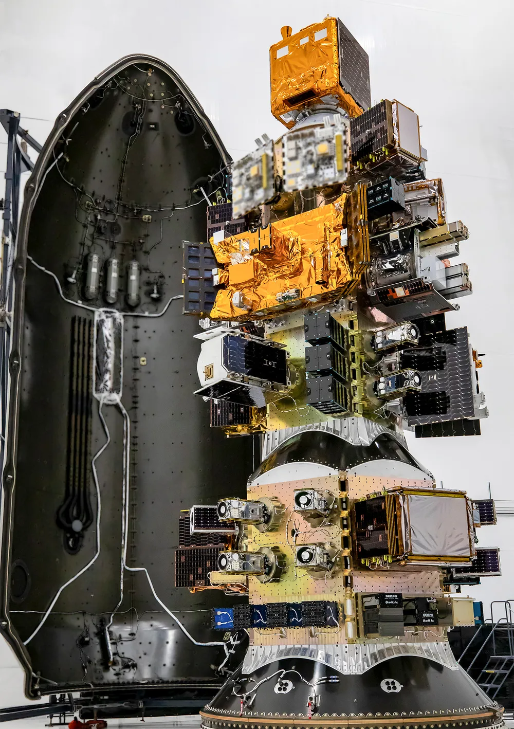 Technicians encapsulate rideshare payloads inside a Falcon 9 dispenser ahead of a SpaceX Transporter mission. Illustrative.