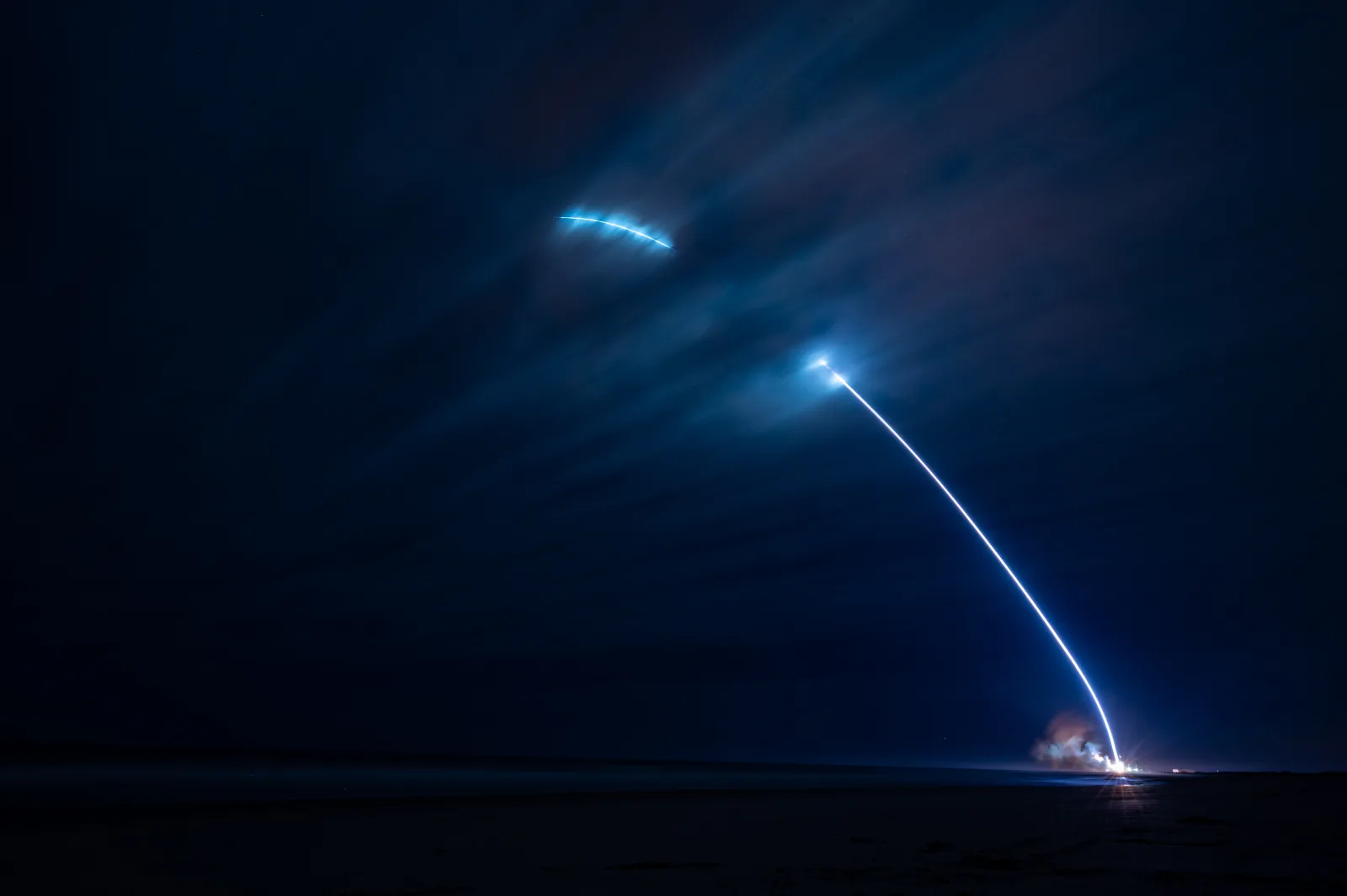 Long-exposure of Blue Origin's New Glenn lifting off at night from Space Launch Complex 36, Cape Canaveral — the arcing trail traces ascent and the booster's return