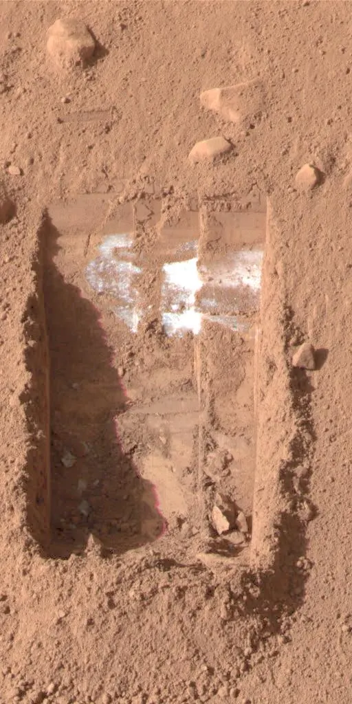Phoenix lander trench in Martian soil exposing white subsurface ice where perchlorates were found